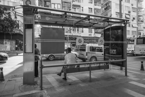 Grayscale Photo of a Man Sitting on Bench