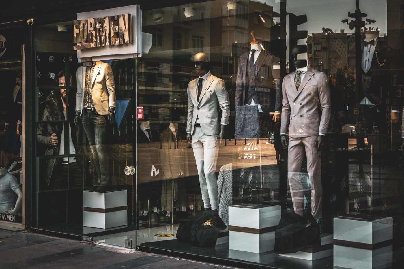 Men's suits on mannequins in an upscale boutique window display