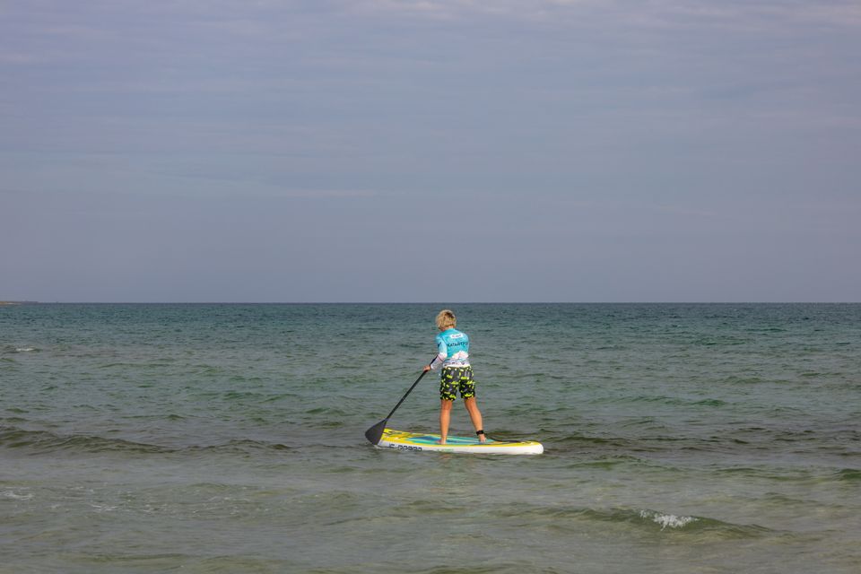 Person, die auf einem ruhigen Meer unter klarem Himmel paddelt und die Freizeit im Freien genießt.