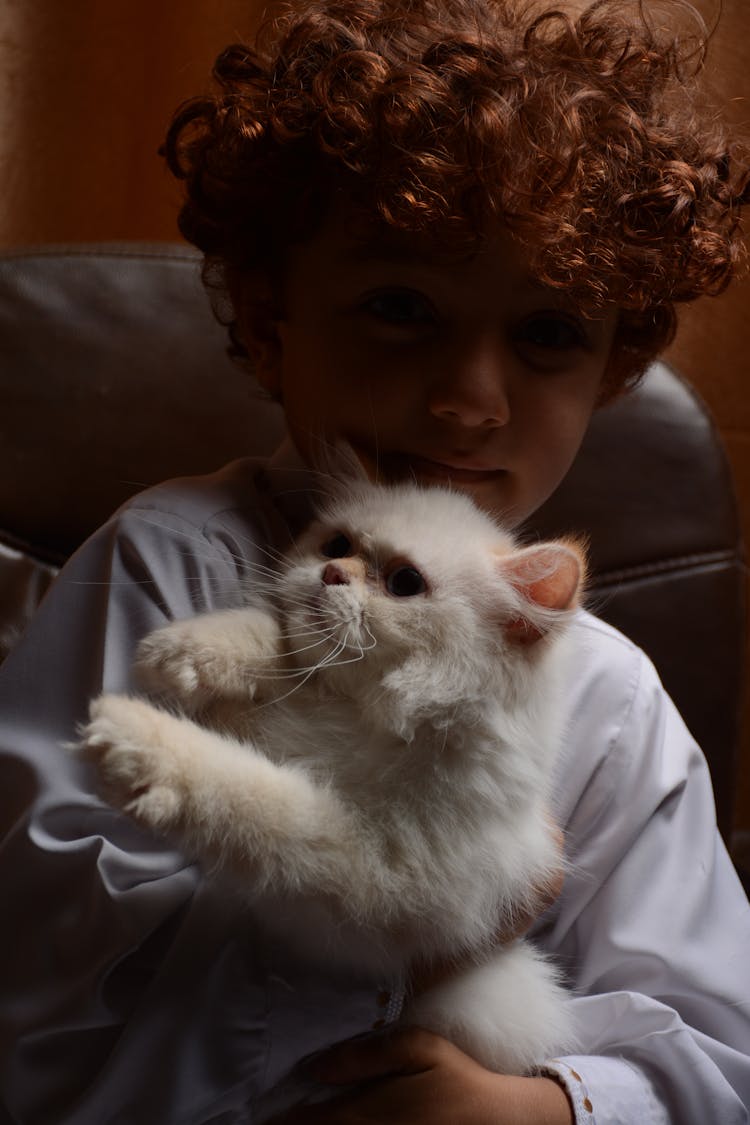 A Boy Cuddling A White Cat