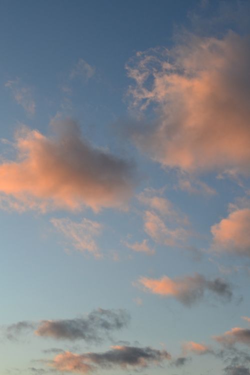 Free Peaceful cloudscape at sunset with pastel pink clouds against a clear blue sky. Ideal for nature and meteorology themes. Stock Photo