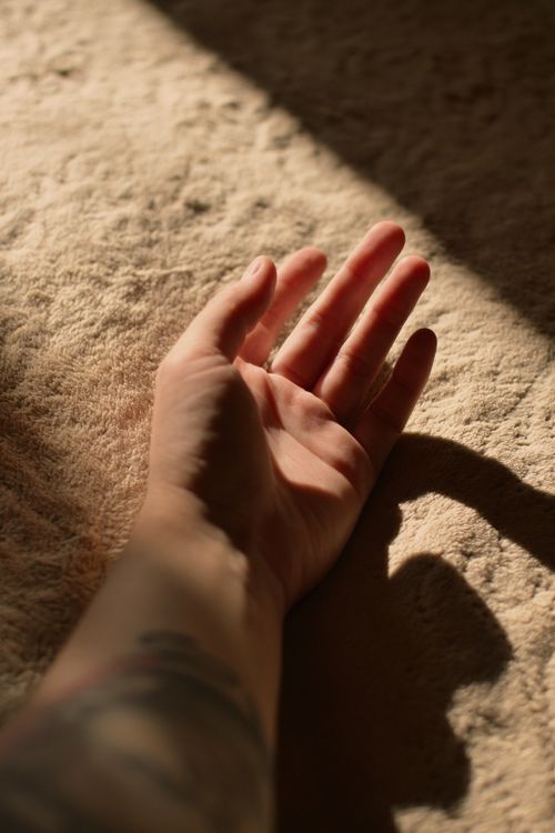 Free A close-up of a hand with artistic shadows in warm light on a textured surface. Stock Photo
