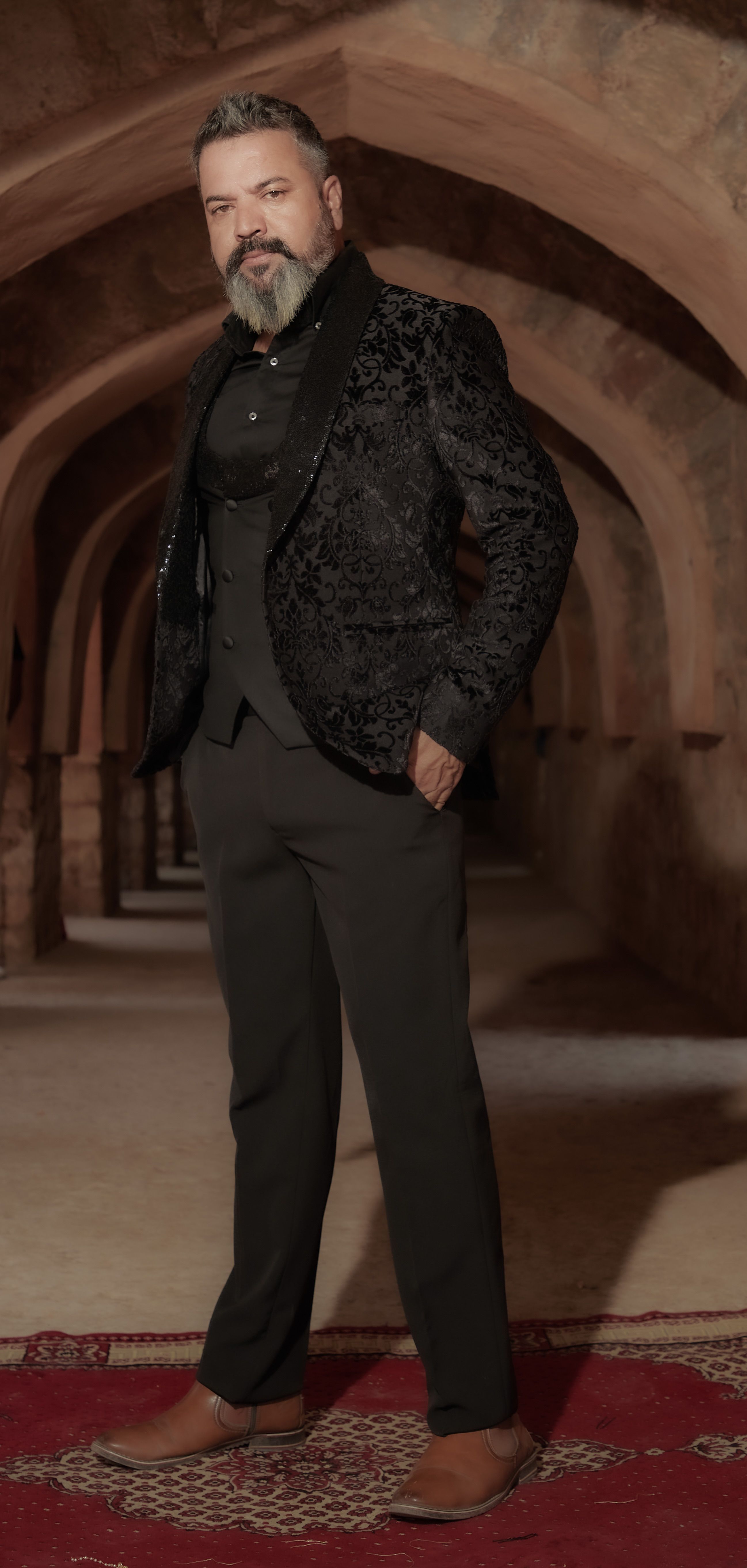 Mature man in stylish suit poses confidently in historic archway with ambient lighting.