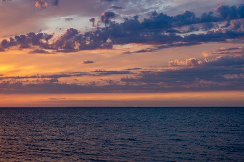 Free Stunning ocean view at sunset with vivid sky hues and scattered clouds. Stock Photo