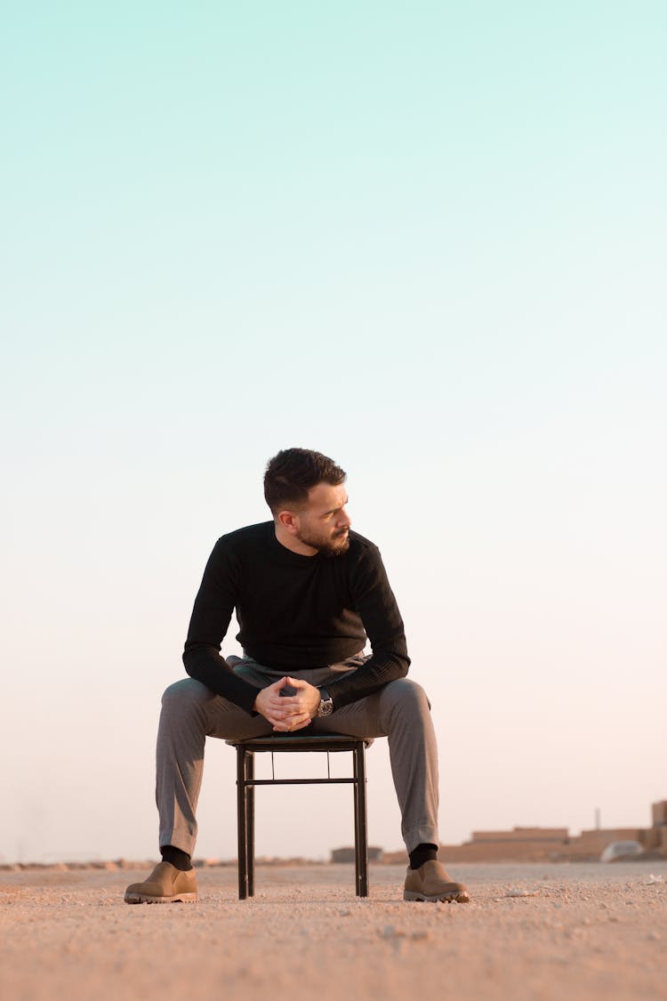 Man In Black Long Sleeves Sitting On The Chair While Looking Afar 