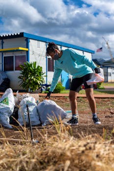 A woman collects trash in an outdoor cleanup effort, promoting environmental protection.