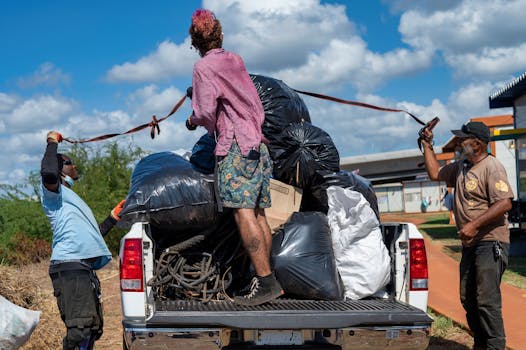 Volunteers loading garbage bags onto a truck during an environmental cleanup event.