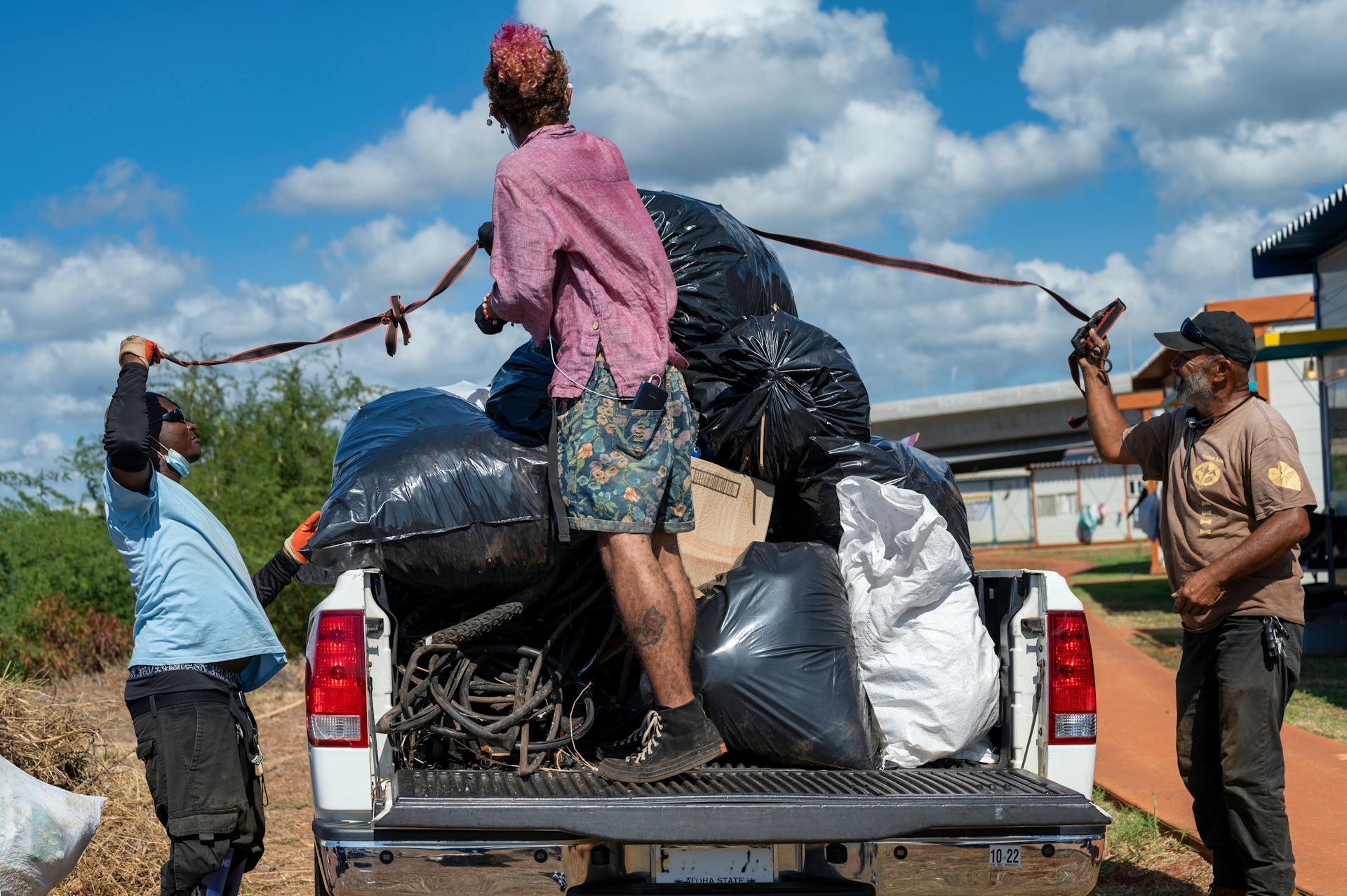 Volunteers loading garbage bags onto a truck during an environmental cleanup event.