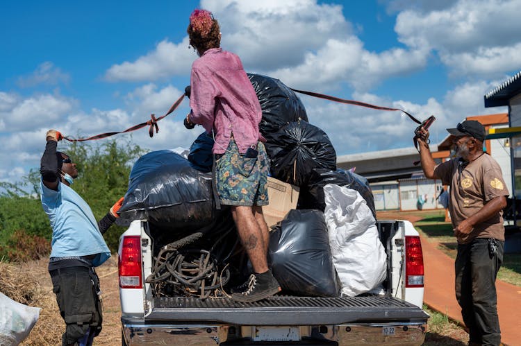 Volunteers Loading Up The Garbage Bags In A Pickup Truck