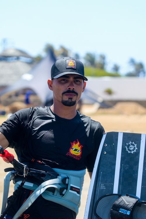 Free Man with beard and cap holding kitesurfing equipment on sunny Adicora beach. Stock Photo