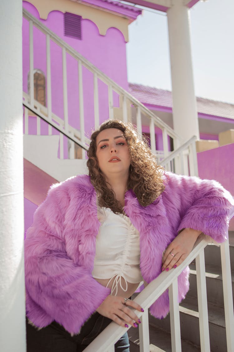 A Woman In Purple Fur Coat Standing On The Stairs