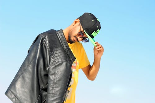 Man Holding His Black And Green Flat-brimmed Cap