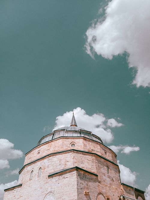 Free Low angle view of a historic dome with a minaret set against a bright cloudy sky, showcasing architectural elegance. Stock Photo