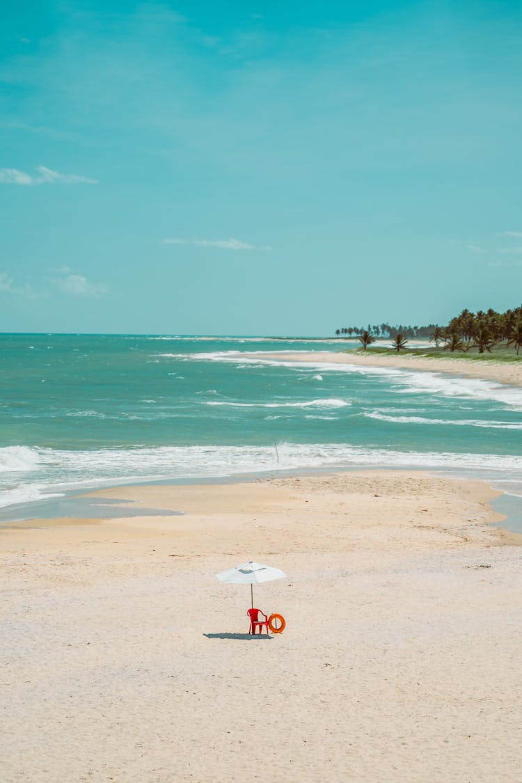 Empty Life Guard Chair At The Beach With A White Sunshade