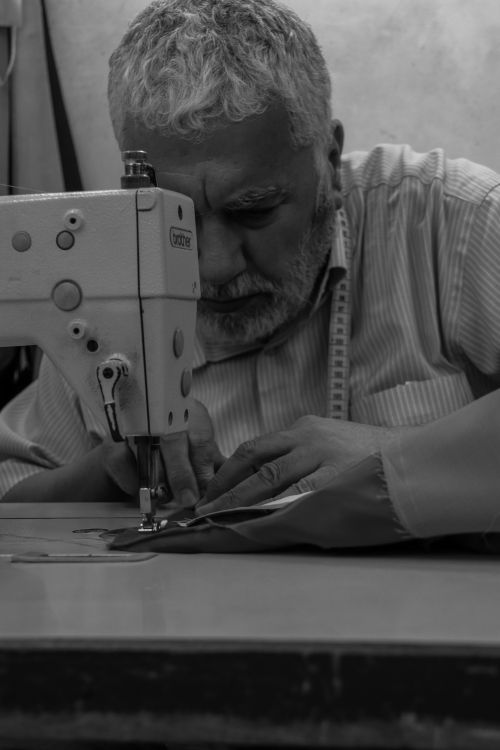 Free A senior tailor focused on sewing at a machine in a monochrome setting. Stock Photo
