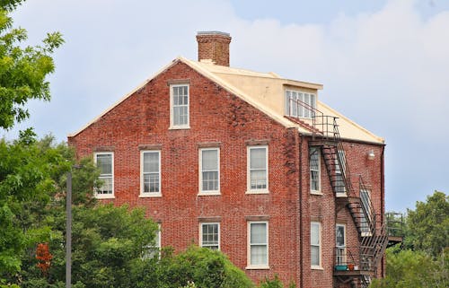 House Made of Bricks Near Green Trees Under Blue Sky