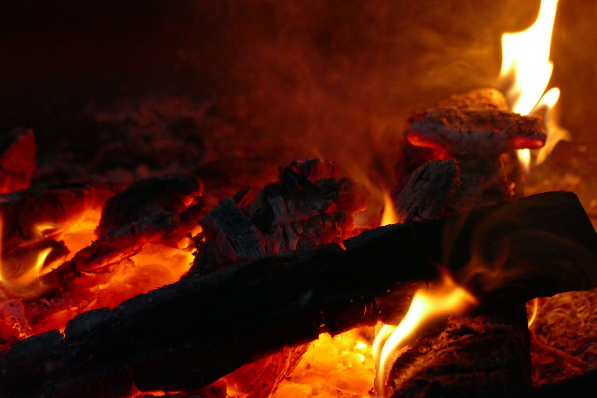 Warm glowing embers of a campfire with dancing flames