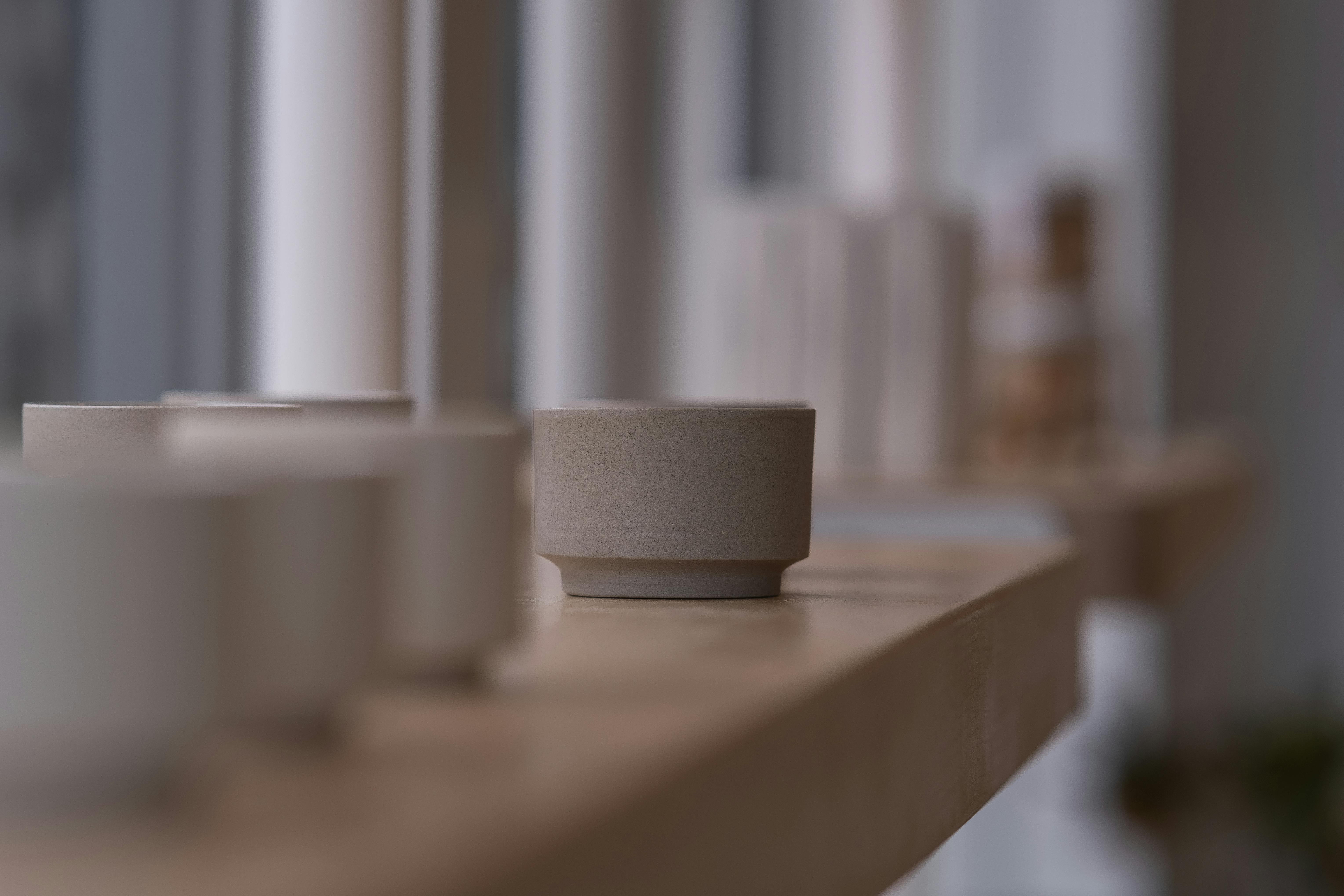 Minimalist design with ceramic pots on a wooden shelf by a window.