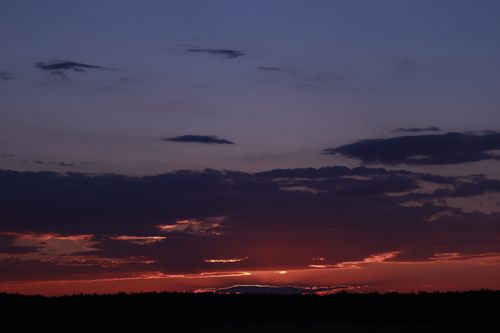 Free Beautiful sunset with dramatic clouds and mountains in silhouette, creating a serene landscape. Stock Photo
