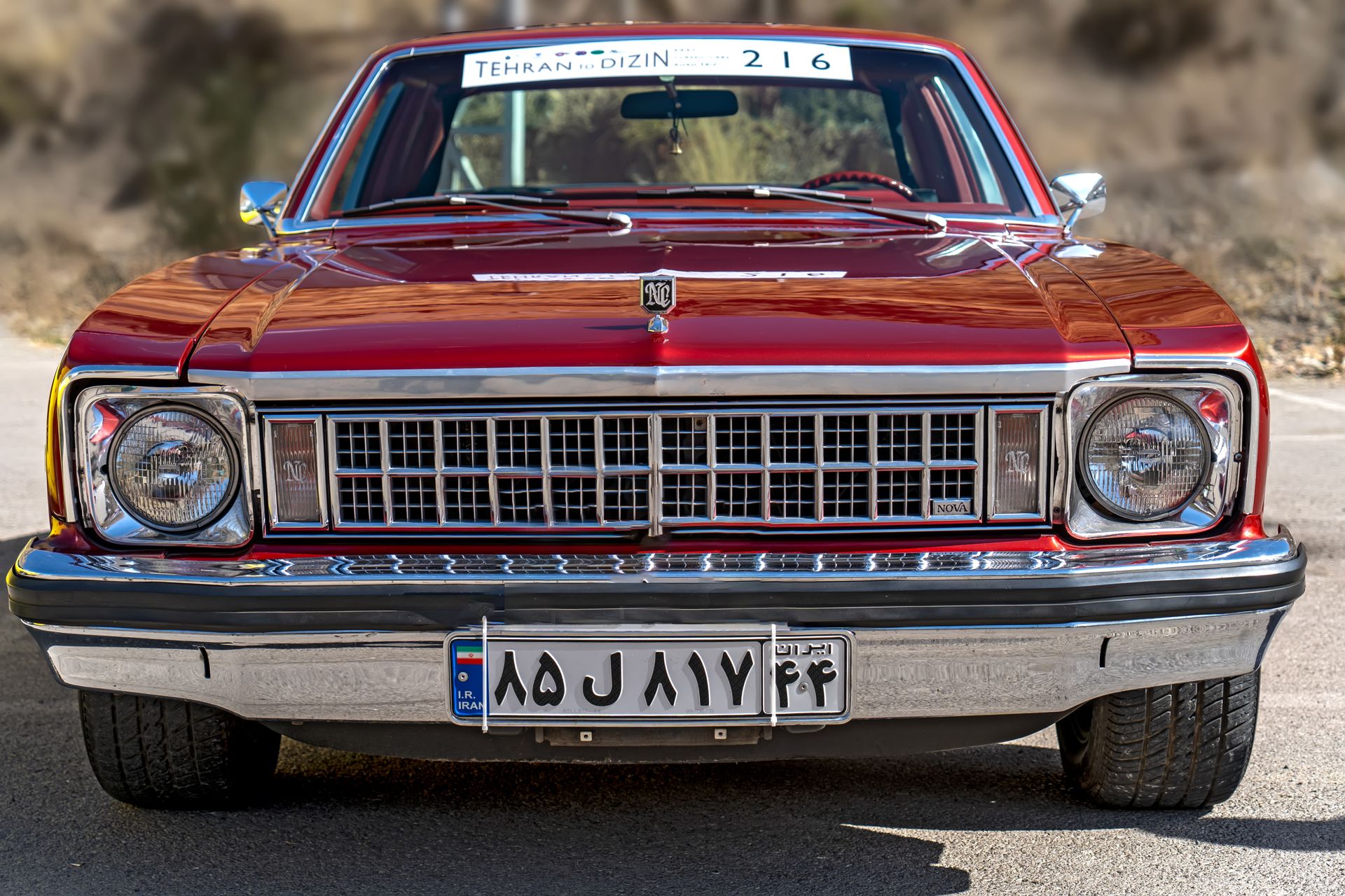 Stunning red Chevrolet Nova Classic Sedan parked outdoors in Iran, displaying a vintage allure.