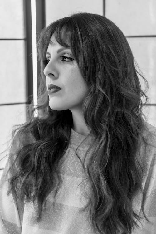 Woman in Long Wavy Hair Looking at the Window