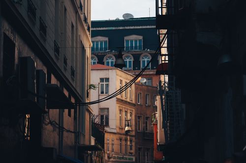 Free Narrow city alleyway with historic buildings and overhead cables, conveying urban charm and connectivity. Stock Photo