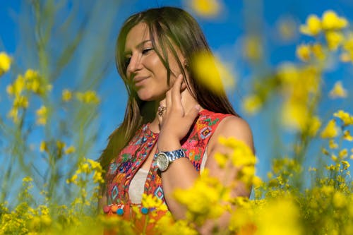 Free Woman Wearing Gray Watch Standing on a Bed of Yellow Flowers Stock Photo