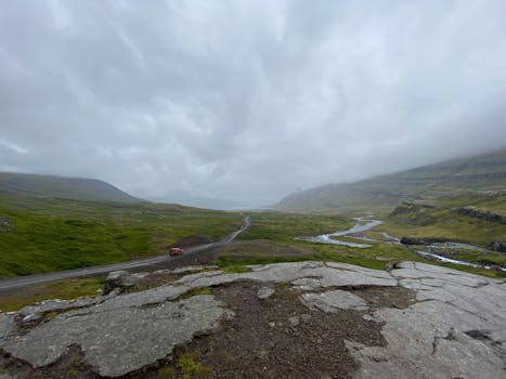 Scenic view of a rural road through Iceland's vast, foggy landscape.