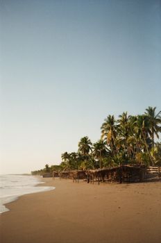 Tranquil beach scene in Poneloya, Nicaragua with palm trees and gentle waves at sunset.
