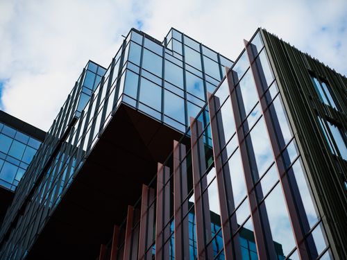 Free Dynamic low angle shot of a contemporary glass facade reflecting the sky. Stock Photo