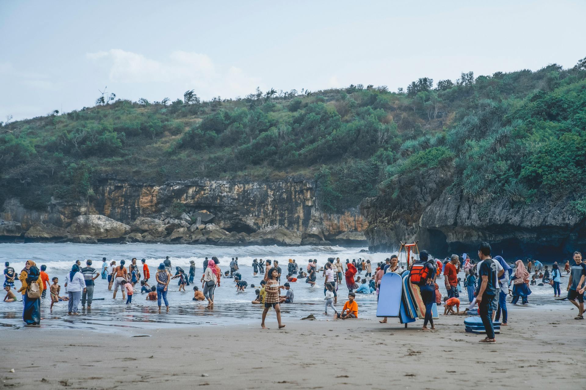 Sunny day at a vibrant Indonesian beach with tourists enjoying the seaside.