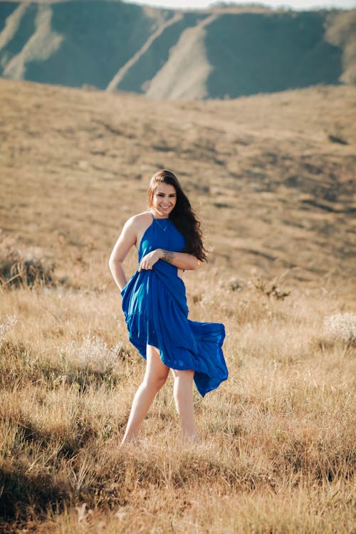 Woman in Blue Dress Standing on Dry Grass