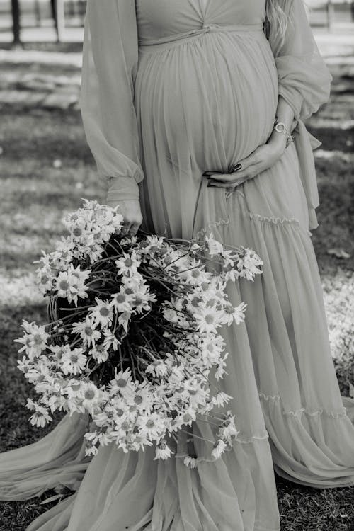 Photo of a Pregnant Woman Standing with Flowers Bouquet