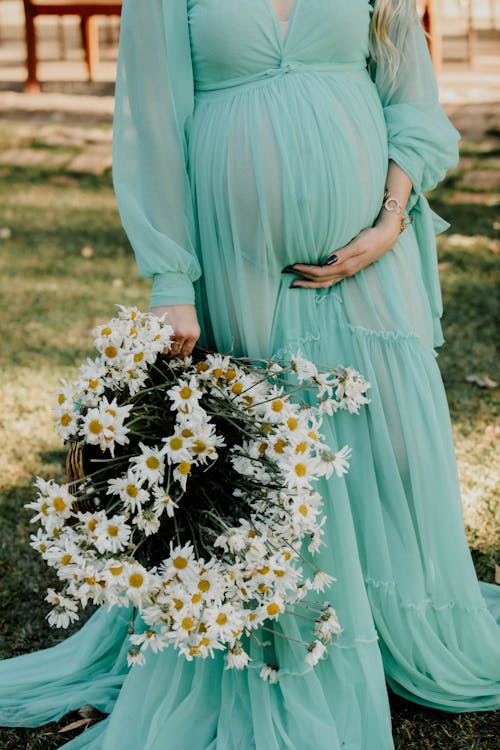 Pregnant Woman in Dress with Bouquet of Daisies