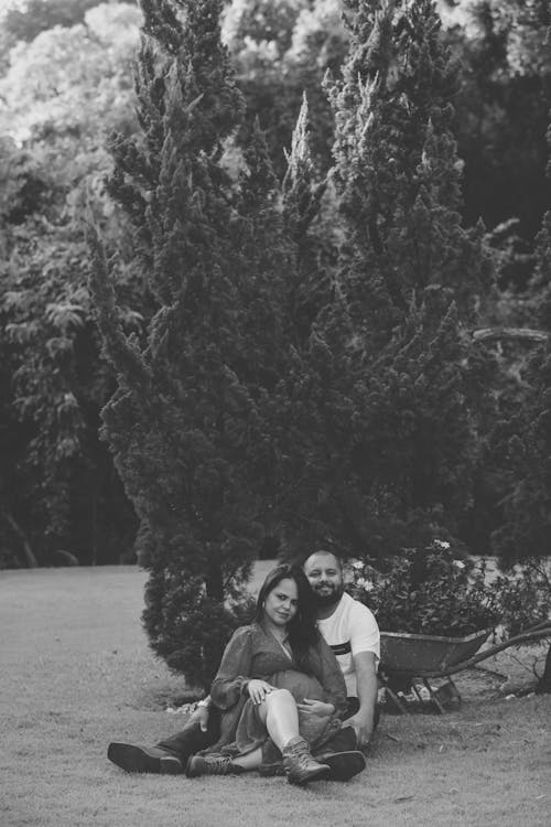 Pregnant Woman with Partner Sitting on Grass in Garden