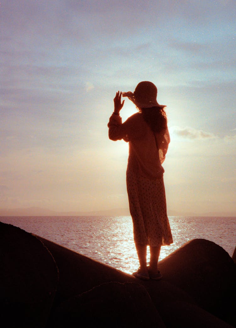 Silhouette Of Woman In Dress Against Sunrise