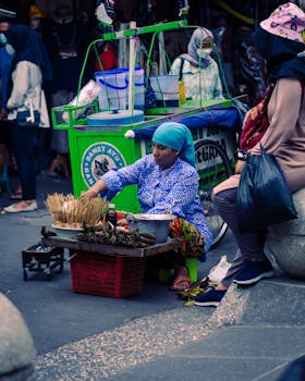 A woman street vendor selling traditional snacks on a vibrant street in Yogyakarta, Indonesia.