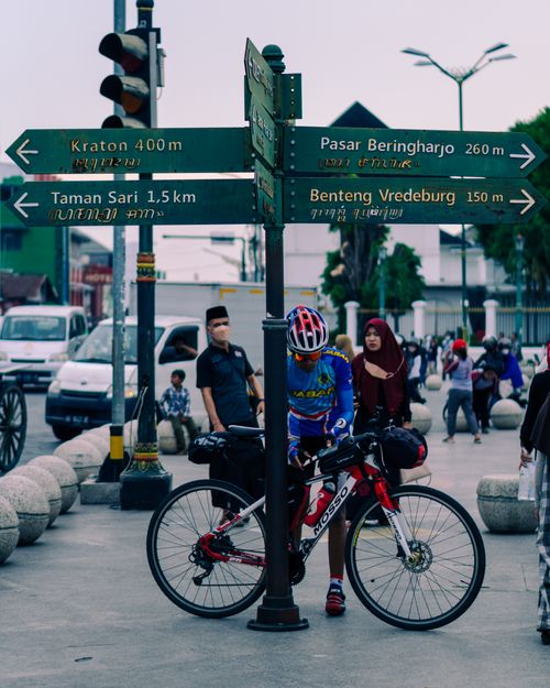Free A cyclist checks directions at a busy intersection in Yogyakarta, Indonesia, near historic landmarks. Stock Photo