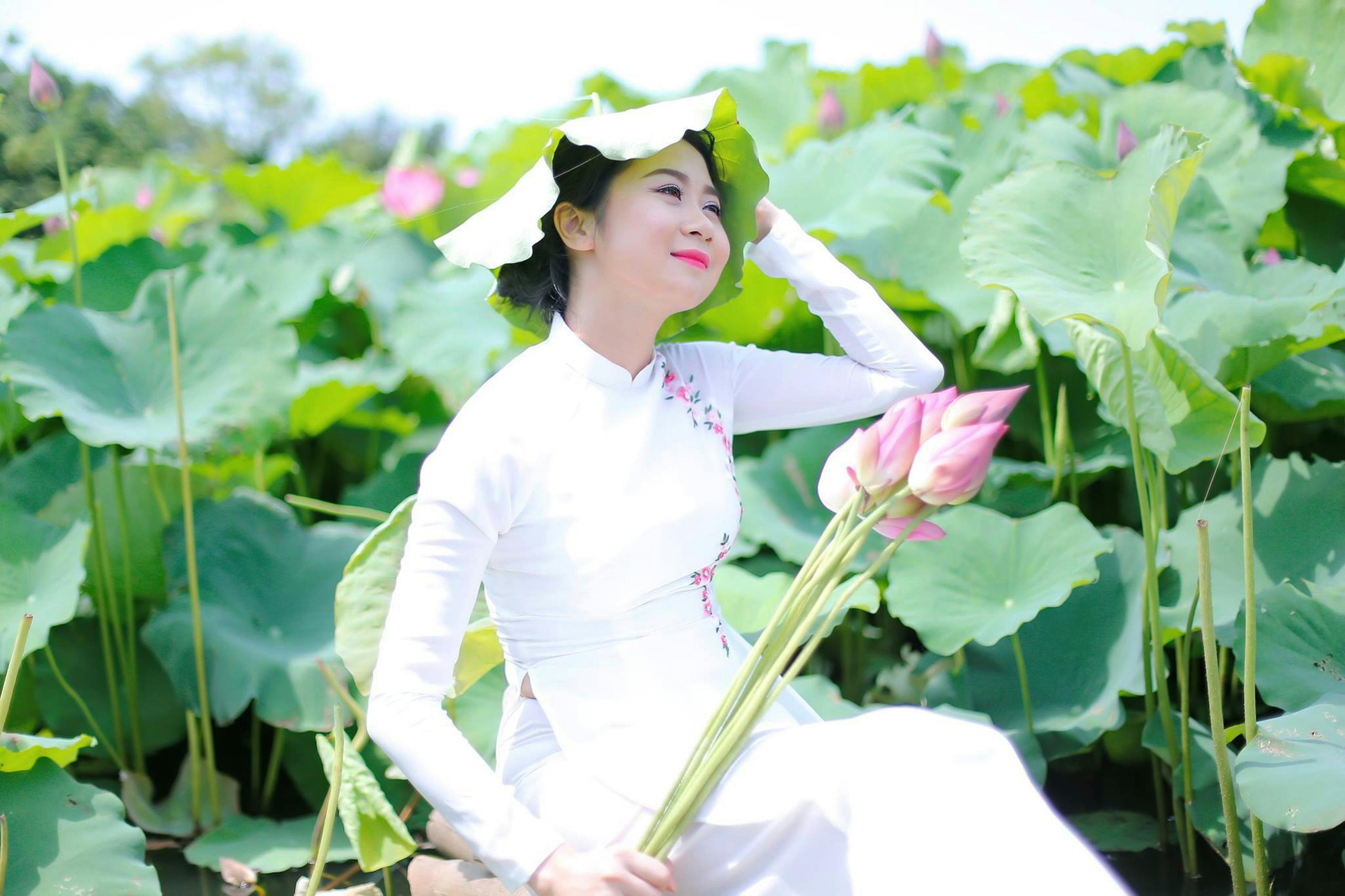 A Woman in Red Tank Top and Black Skirt Standing Near Green Plants ...