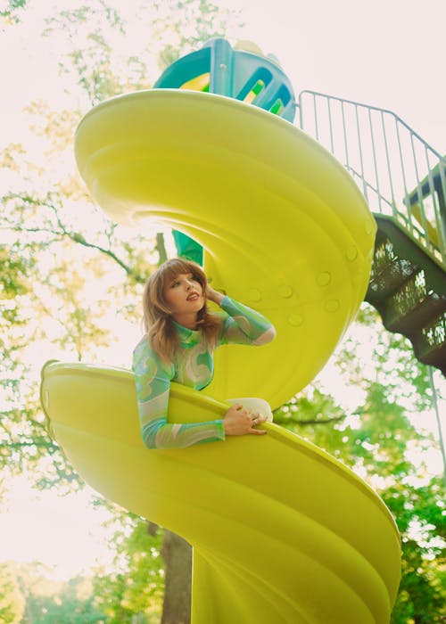 Young Woman Sitting on a Spiral Slide on a Playground 