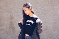 一位穿着休闲装的时尚年轻女子在户外的纹理墙前摆姿势