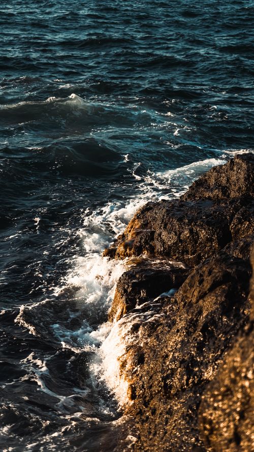 Free Capture of powerful ocean waves splashing against rugged rocks during daylight. Stock Photo