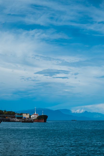 Tranquil coastal scene featuring a docked ship under a vast blue sky.
