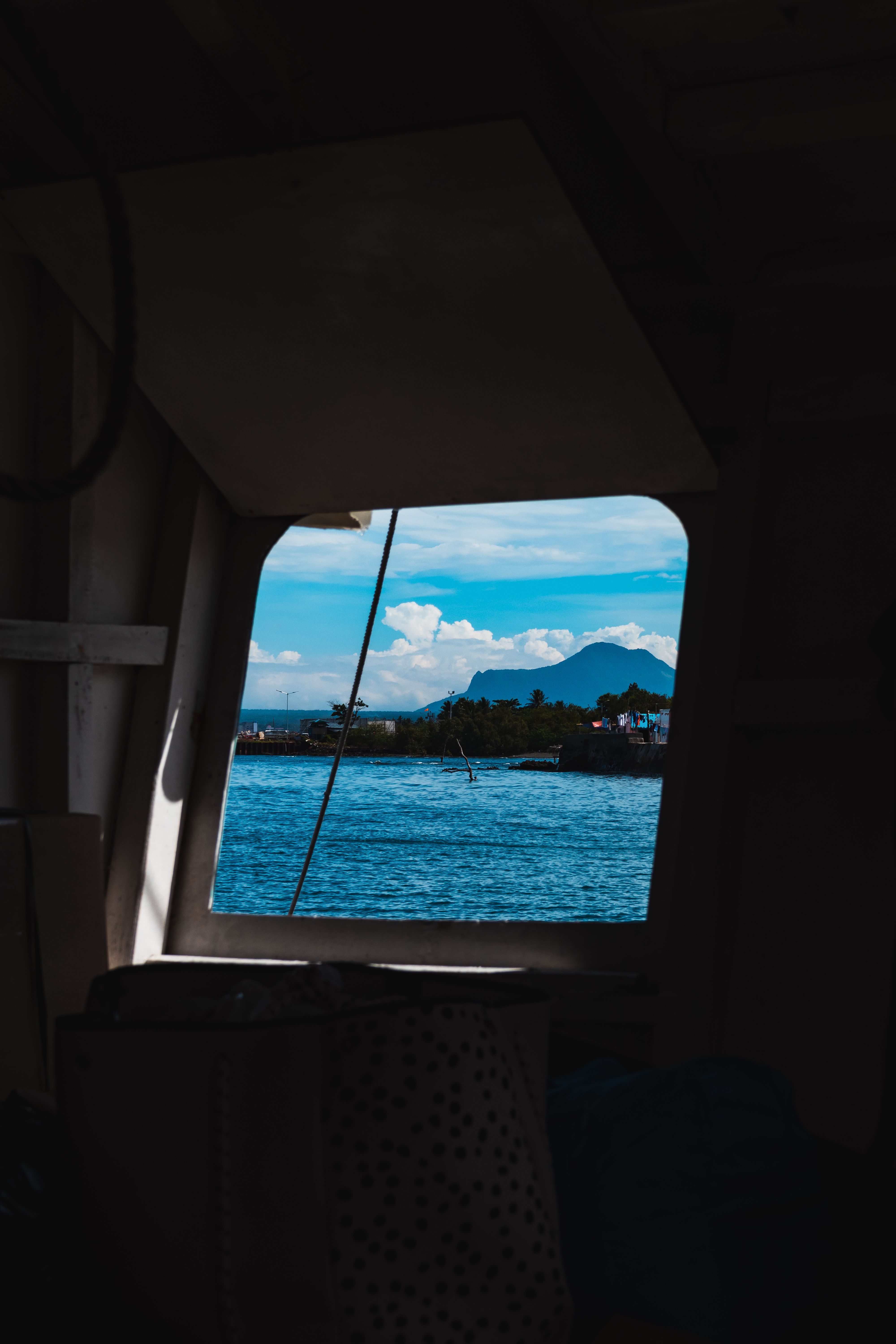 A serene view of water and distant mountains seen through a boat window, capturing a moment of tranquility.