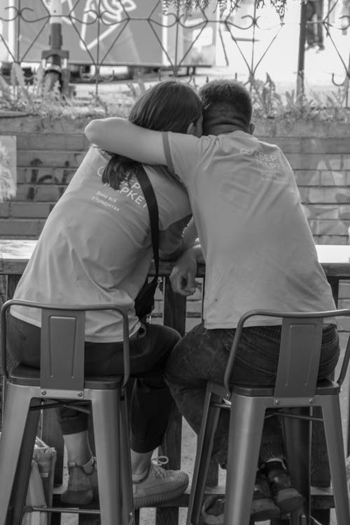 Grayscale Photo of a Couple Sitting Close Together