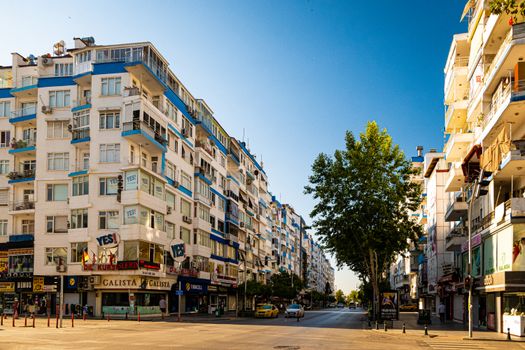 Daytime city street scene with modern apartment buildings and a clear blue sky.