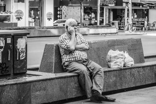 Man Sitting on Bench in City