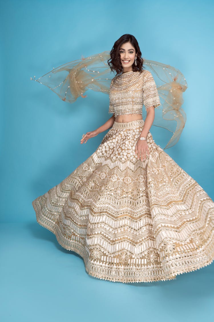 Studio Portrait Of A Beautiful Brunette Posing In A Long White And Gold Dress