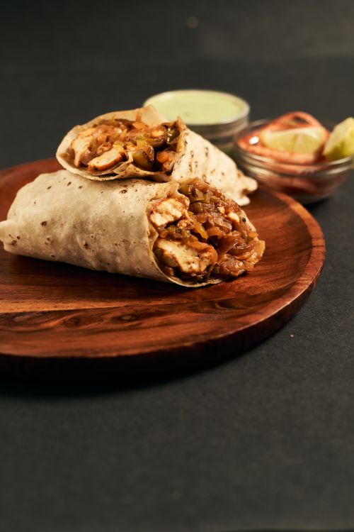 Free Mouth-watering chicken wraps served with dips on a wooden plate, perfect for lunch. Stock Photo