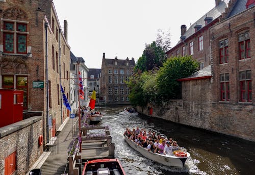People Riding on Boat on River Between Buildings